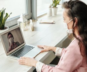 Frau mit Maske am Laptop